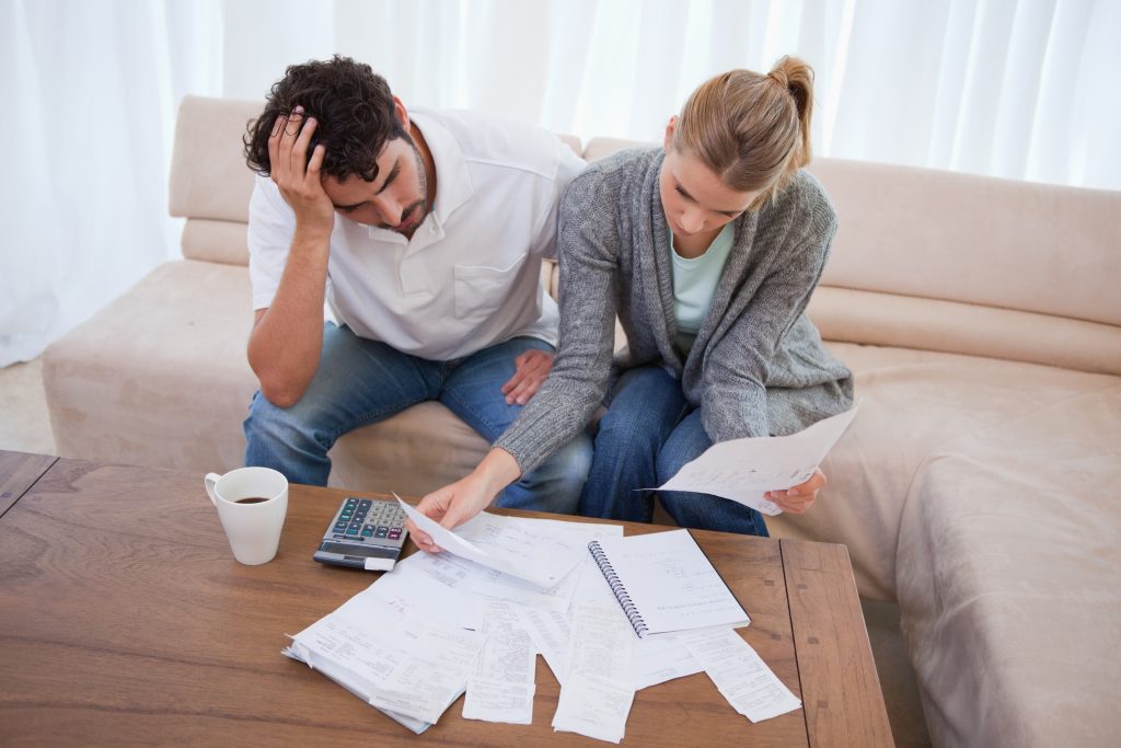 Image of a couple worried going through their bills - Represents that you should learn the truth about budget and never worry about being able to pay your bills anymore