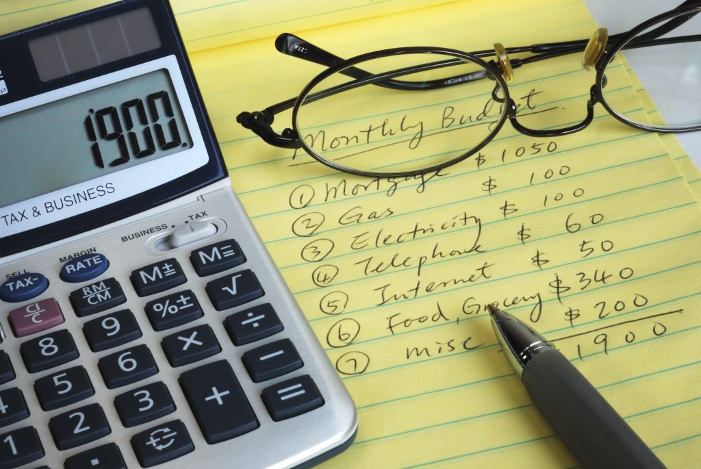Image of a calculator, glasses, a pen and a notepad with expenses written on it - represent that you should learn the truth about budget and stop taking notes of every single dollar you spend