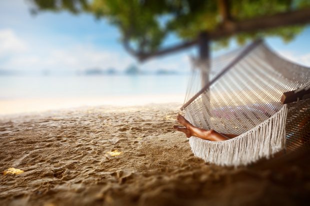 Image of a woman laying on a hammock at the beach - Say Goodbye to Money Stress and enjoy the life you deserve
